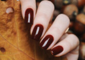 Burgundy brown manicure with yellow leaf on a background of acorns